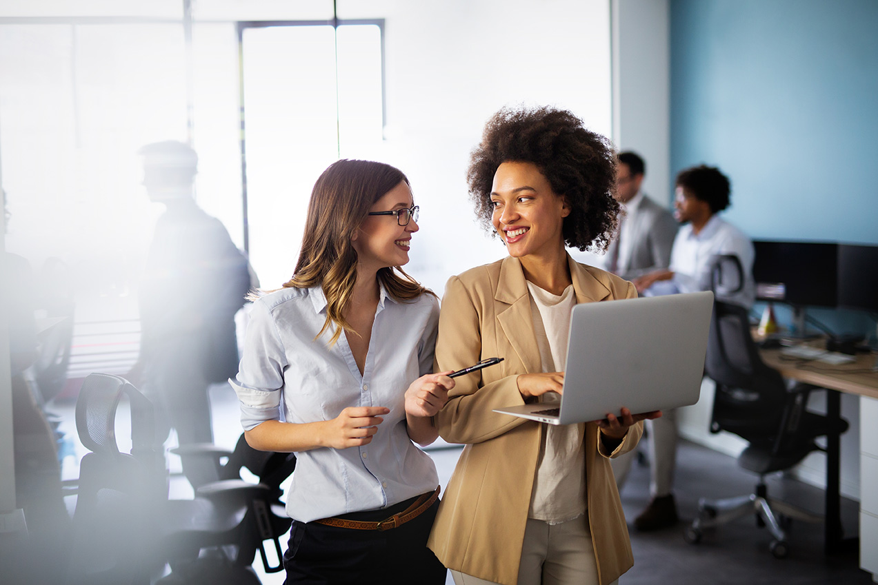 two people standing outside looking at a pc and having a meeting
