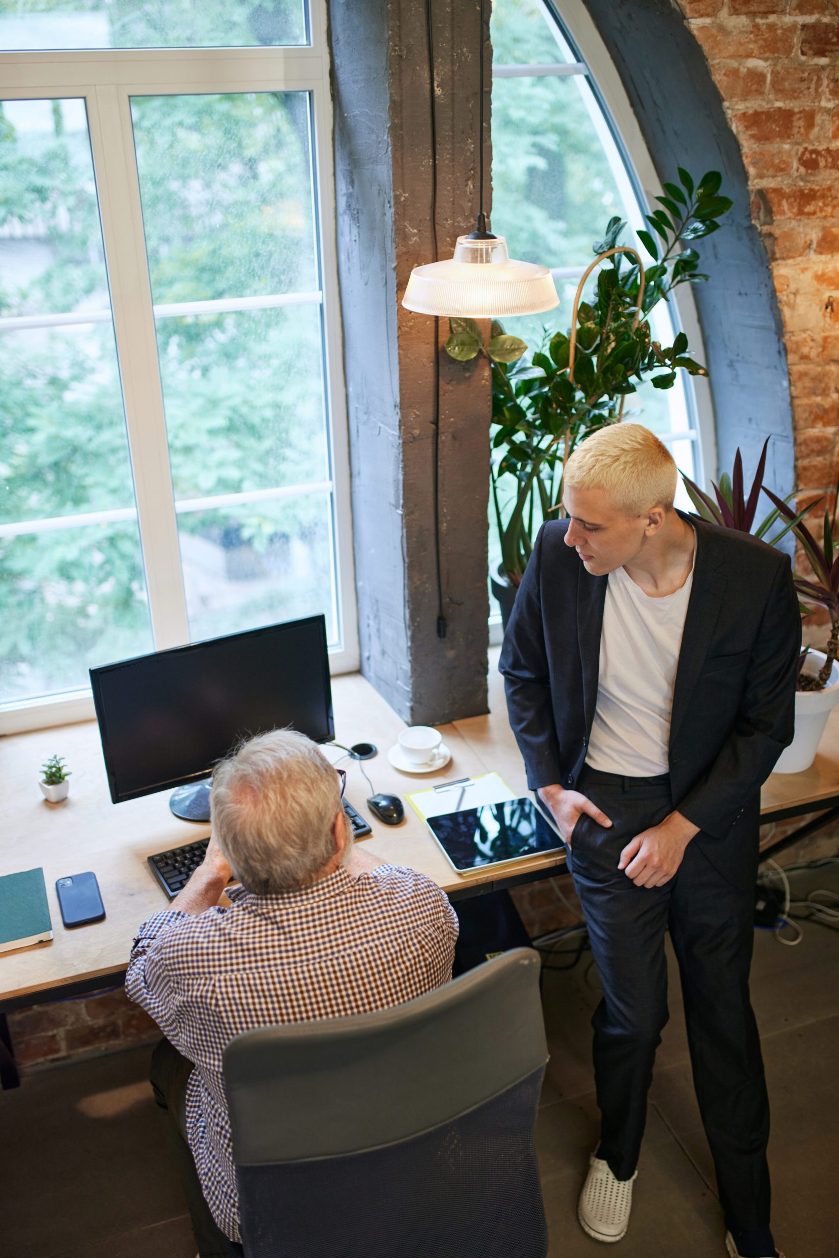 two person meeting with one sitting on a chair at the table and one is sitting on the table.